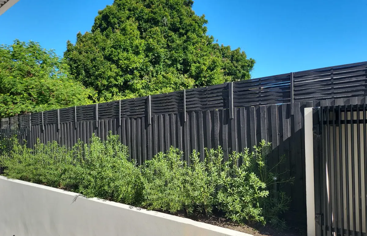 Long black fence with lattice top along garden