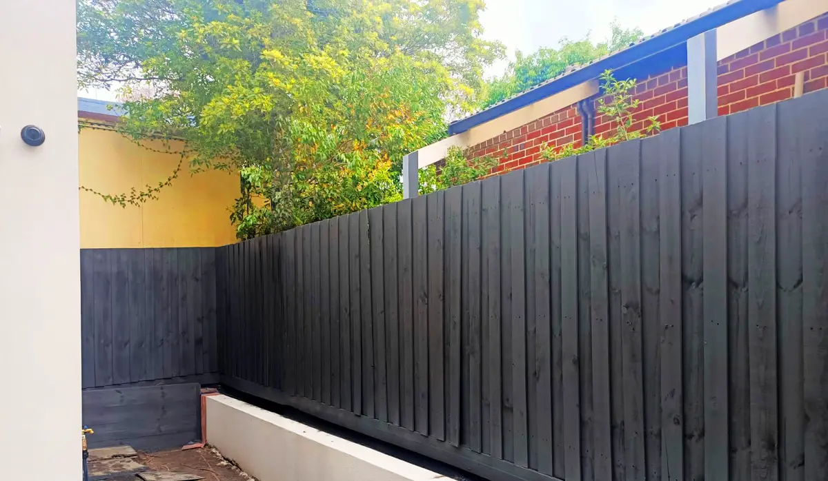 Dark fence above rendered planter wall